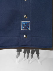 K-Short bleu, en coton et plastique recyclés, détail de l'écusson brodé logo, bleu et argenté sur fond bleu marine